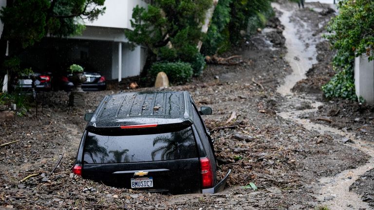 An SUV sits buried by a mudslide, Monday, Feb. 5, 2024, in the Beverly Crest area of Los Angeles. A storm of historic proportions unleashed record levels of rain over parts of Los Angeles on Monday, endangering the city&#39;s large homeless population, sending mud and boulders down hillsides dotted with multimillion-dollar homes and knocking out power for more than a million people in California. (AP Photo/Marcio Jose Sanchez)