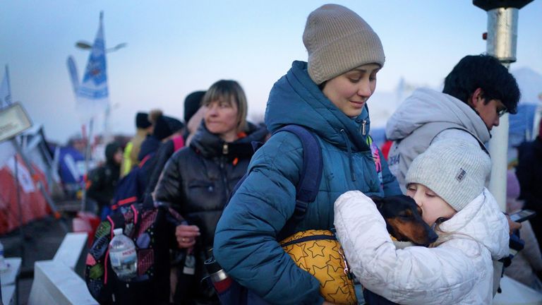 A young girl from Ukraine holds her dog as she waits with her mother for a bus to refuge accommodation after they crossed the border point from Ukraine into Medyka, Poland. Picture date: Saturday March 19, 2022.