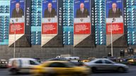 Cars drive past electronic screens on the facade of a building showing an image of Vladimir Putin, in Moscow. Pic: Reuters