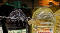 Olive and sunflower oil bottles are displayed for sale in Malaga, protected by a padlock and a chain to prevent theft. Pic: Reuters