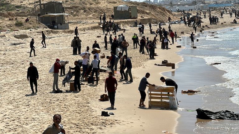 Palestinians gather on a beach as they collect aid airdropped by an airplane.
Pic: Reuters