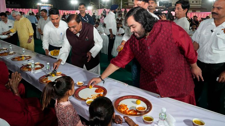 Mukesh Ambani, center left, and his son Anant Ambani, third right, serving food to the community earlier this week. Pic: Reliance group via AP