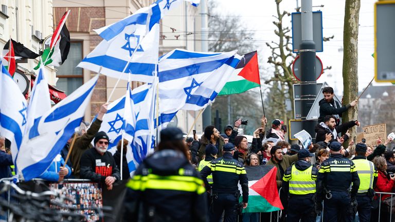 Demonstrators hold Palestinian and Israeli flags. Pic: Reuters/Piroschka van de Wouw