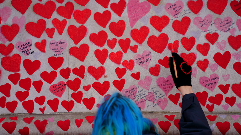 A volunteer from the Covid-19 Bereaved Families for Justice campaign group paints a heart on the National COVID Memorial Wall. Pic: PA
