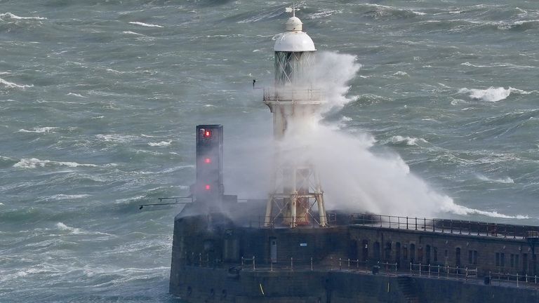 Waves crash over a lighthouse on the wall of Dover harbor in Kent. Forecasters say areas of rain, sleet and mountain snow are moving north across the UK as holidaymakers prepare to embark on their Easter journeys. Image date: Thursday, March 28, 2024.