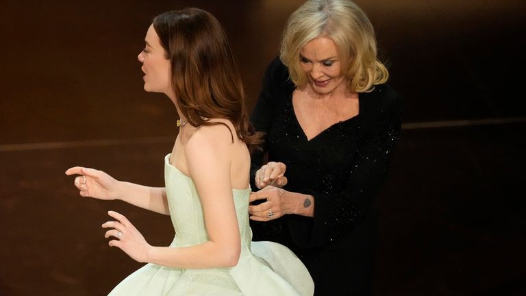 Jessica Lange, right, adjusts Emma Stone&#39;s dress during the Oscars on Sunday, March 10, 2024, at the Dolby Theatre in Los Angeles. (AP Photo/Chris Pizzello)