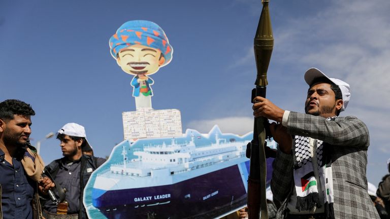 A Houthi follower holds a rocket launcher besides an image of the Galaxy Leader cargo ship, 7 February. Pic: Reuters