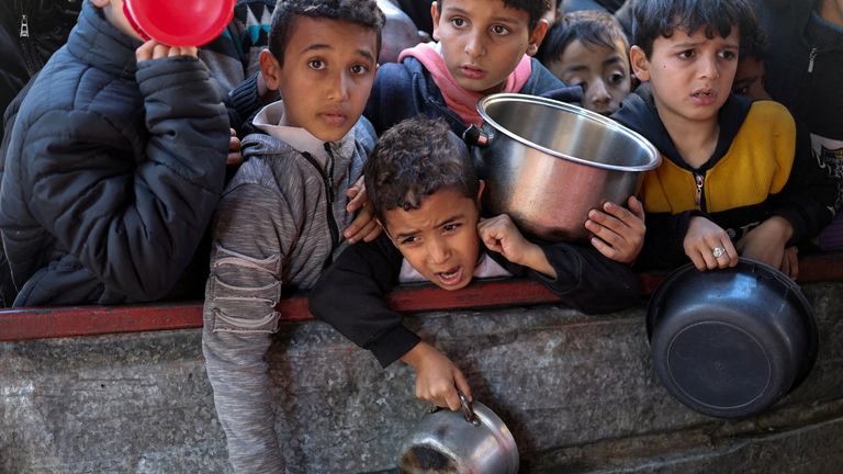 Palestinian children wait to receive food prepared from the charity kitchen in Rafah.Image source: Reuters