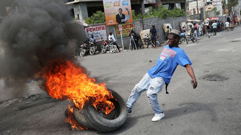 A man kicks burning tyres. Pic: Reuters