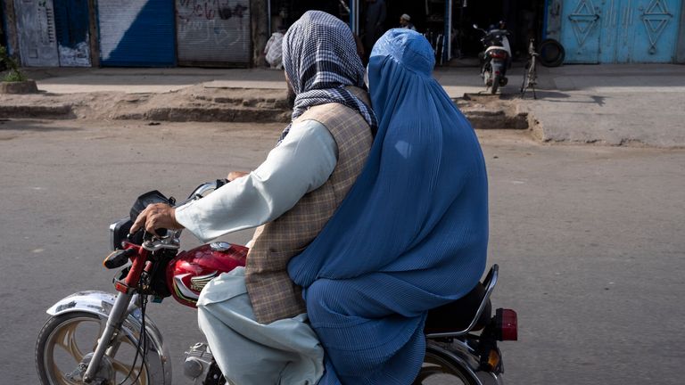 A man carries a woman dressed in a burqa on his motorcycle in Herat, Afghanistan, Sunday, June 4, 2023. (AP Photo/Rodrigo Abd)
