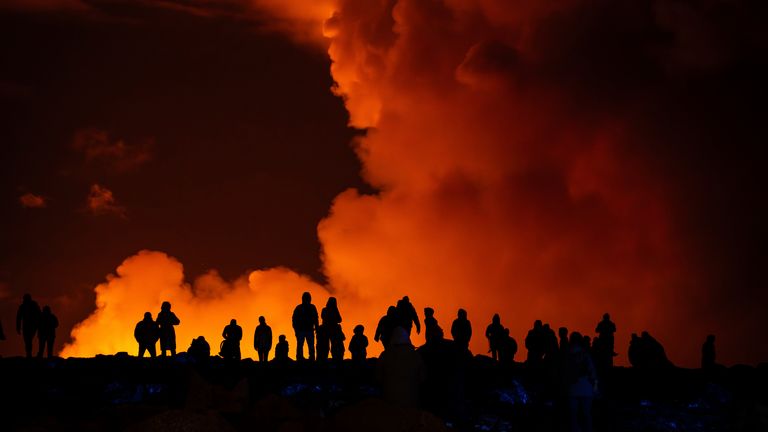 Spectators watch plumes of smoke from volcanic activity between Hagafell and Stóri-Skógfell, Iceland, Saturday, March 16, 2024. (AP Photo/Marco di Marco)