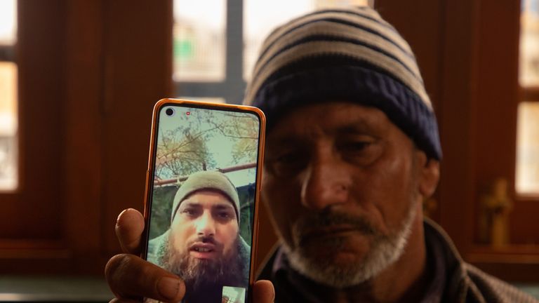 The father of Azad Yousuf Kumar, holds a phone with his son&#39;s picture. Pic: Rex Features
