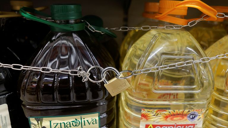 Olive and sunflower oil bottles are displayed for sale in Malaga, protected by a padlock and a chain to prevent theft. Pic: Reuters