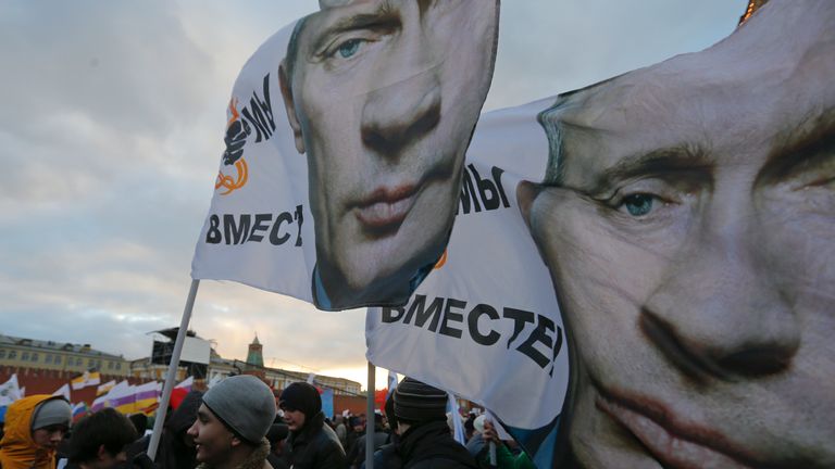 People in Moscow wave flags bearing the face of Vladimir Putin as they show their support for Russia&#39;s annexation of Crimea in 2014. Pic: Reuters