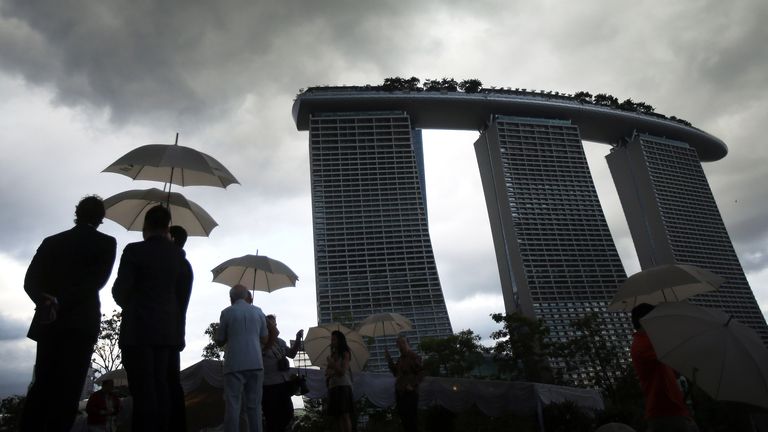People hide under the shelter of umbrellas with the Marina Bay Sands seen in the background on Friday Jan. 18, 2013 in Singapore which is experiencing torrential rain during this time of the year..(AP Photo/Wong Maye-E)