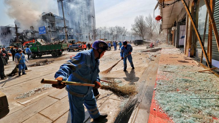 Workers clean up debris on the ground near the site of a restaurant explosion in Sanhe.
Pic: Cina Daily/Reuters