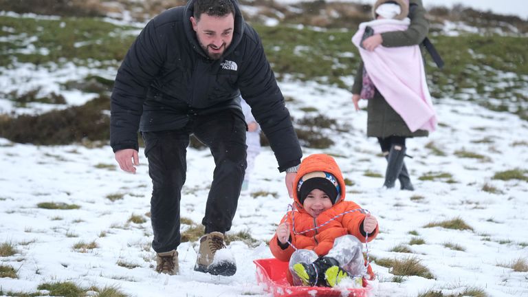 Jack Campbell pushes his son Harvey on a sledge in the snow on Dartmoor. Snow has fallen in parts of south-west England and Wales. Forecasters say an area of rain, sleet and hill snow is moving north across the UK as holidaymakers prepare to embark on Easter getaways. Picture date: Thursday March 28, 2024.