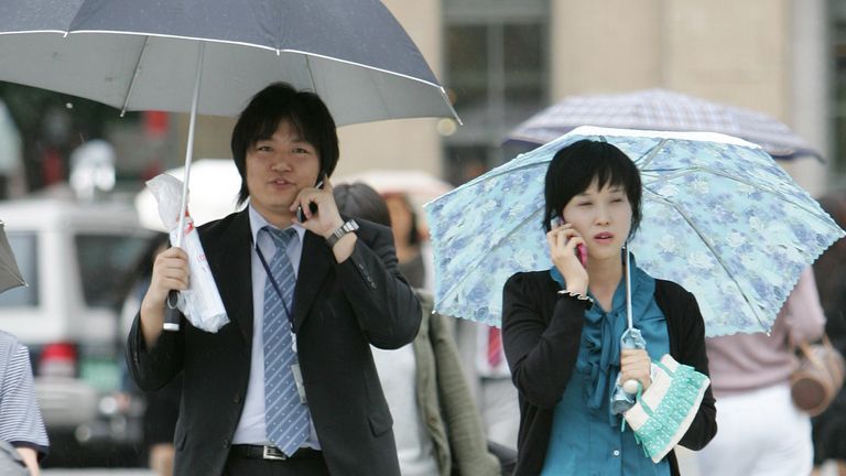 A man and a woman talk on their mobile phones as they cross a road in Seoul September 18, 2006. South Korea will cleanse gender stereotypes from its school textbooks where women have long been depicted as housekeepers and men as the breadwinners. The government said on Monday that it would also encourage bigger families to boost the country&#39;s sagging birth rate. REUTERS/Kim Kyung-Hoon (SOUTH KOREA)
