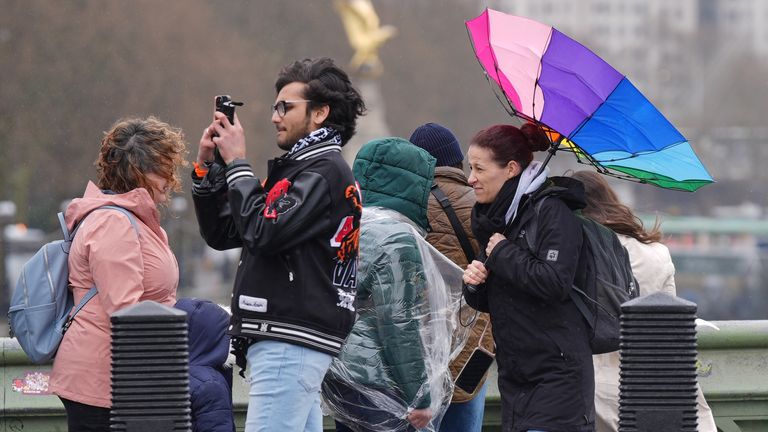 People in the rain walking along Westminster Bridge in London.
Pic: PA