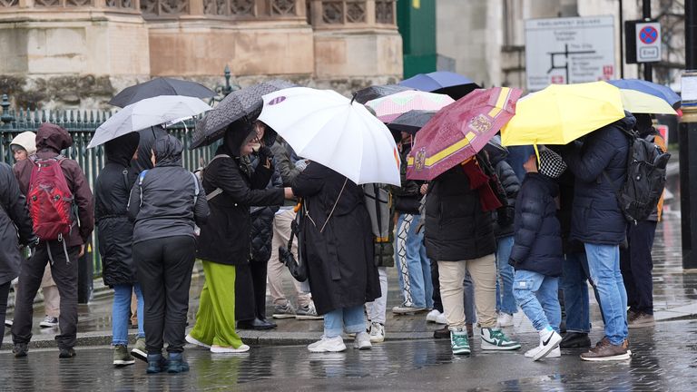 People take shelter from the rain in Westminster, London. Image: PA