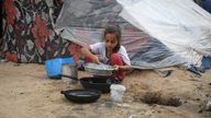 A girl pours water next to a tent in the southern Gaza city of Rafah. Pic: Reuters