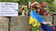 Flowers and a small Ukrainian flag are laid at a shopping center in Murnau, Germany following the fatal stabbings of two men. Pic: AP