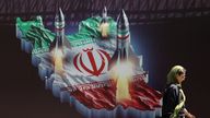 An Iranian woman walks past an anti-Israel banner with a picture of Iranian missiles on a street in Tehran
Pic:WANA/Reuters
