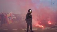 Police officers stand guard as supporters burn flares outside the Metropolitano stadium. Pic: AP