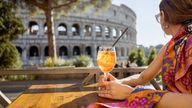 A woman enjoys a drink with a view of the Colosseum in Rome. Pic: iStock