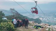 Rescue and emergency team members work with passengers of a cable car transportation system outside Antalya, southern Turkey, Friday, April 12, 2024. At least one person was killed and several injured Friday when a cable car pod in southern Turkey hit a pole and burst open, sending the passengers plummeting to the mountainside below, officials and local media said. Scores of other people were left stranded late into the night after the entire cable car system came to a standstill. (Dia Images via AP)