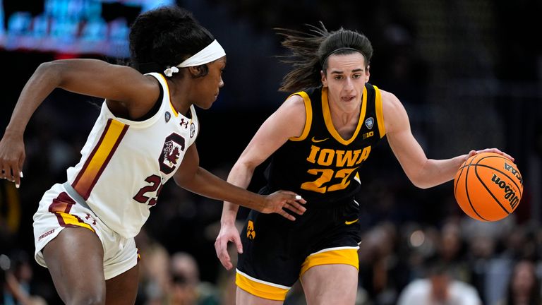 Iowa guard Caitlin Clark (22) steps onto the court in front of South Carolina guard Raven Johnson, left, during the first half of the Final Four college basketball championship game of the women's NCAA tournament , on Sunday, April 7, 2024, in Cleveland.  (AP Photo/Carolyn Kaster)