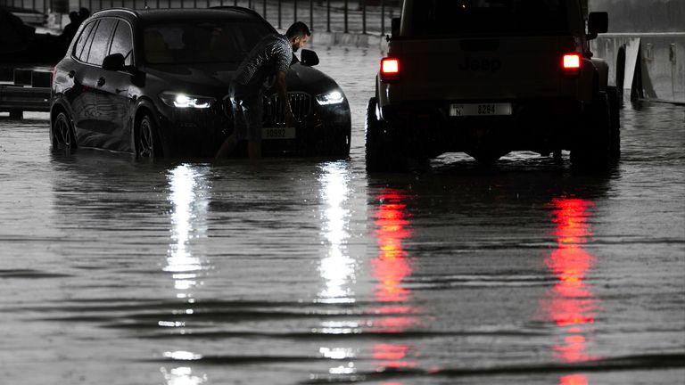 A man tries to work on his stalled SUV in standing water in Dubai.
Pic: AP