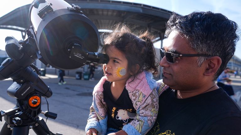 Tawhid Rana  hold his daughter Thia, as she views the sun  at the Indianapolis Motor Speedway.
Pic: AP