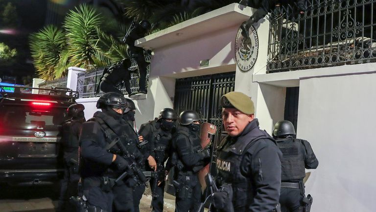 Police are seen climbing over the wall as they forced entry to the premises. Pic: AP