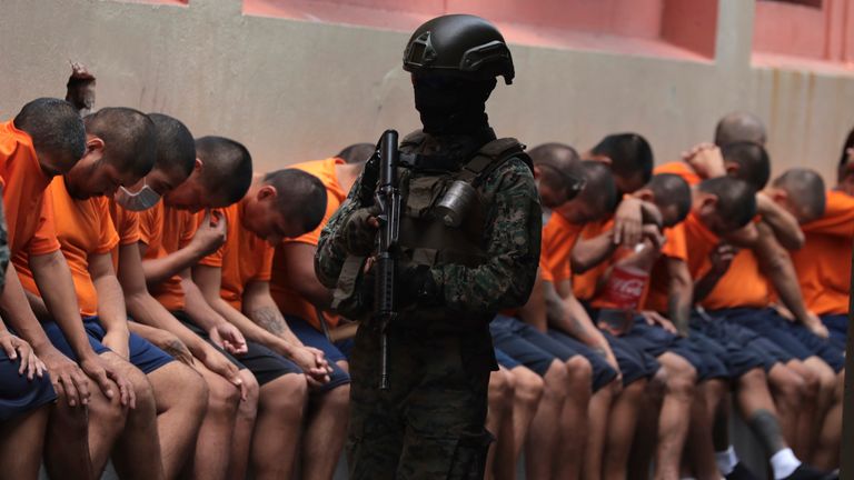 A soldier stands guard over inmates at the Litoral Penitentiary during a press tour organized by the military, in Guayaquil, Ecuador, Friday, Feb. 9, 2024.  According to the military, the tour is to demonstrate that control has been regained inside the prison, considered one of the most violent in the country. (AP Photo/Cesar Munoz)