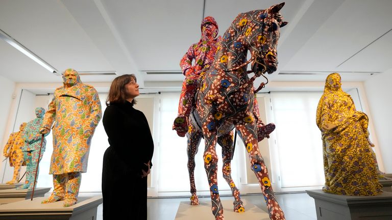 A visitor looks at a sculpture made of fiberglass and hand-painted while taking photos at artist Yinka Shonibare's 