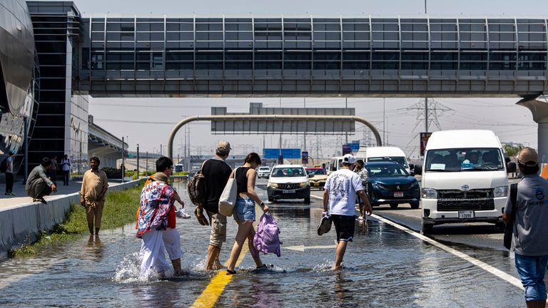 People walk through floodwater caused by heavy rain while waiting for transportation on Sheikh Zayed Road highway in Dubai.
Pic AP
