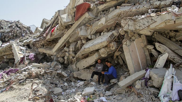 فلسطینی ها در مقابل آوار یک ساختمان مسکونی که توسط حملات اسرائیل در شمال غزه ویران شده است، نشسته اند.  عکس: رویترز