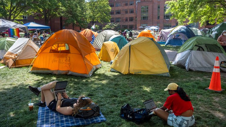 People sit in the shade near tents at a student encampment protesting the war between Israel and Hamas at George Washington University, Monday, April 29, 2024, in Washington.  (AP Photo/Mark Schiefelbein)