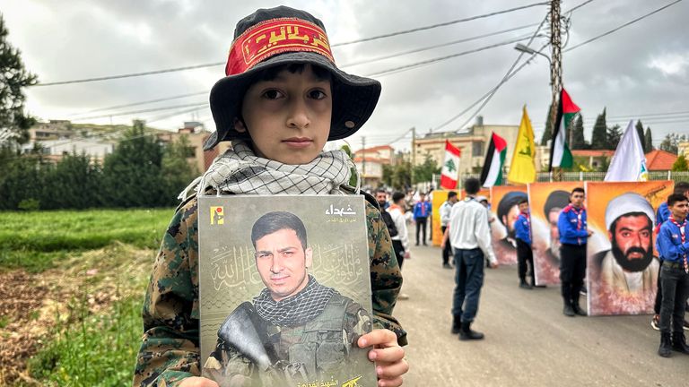 The son of a Hezbollah fighter holds a picture of his dad