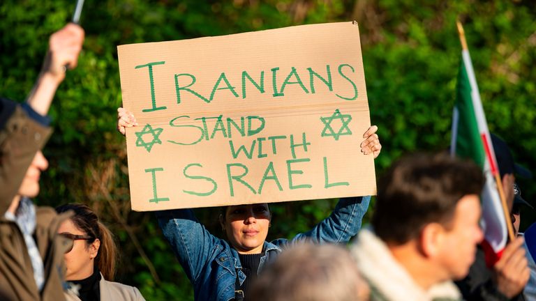 A woman holds a poster reading "Iranians stand with Israel" during a rally on the lawn opposite the Iranian consulate in Germany. Pic: AP
