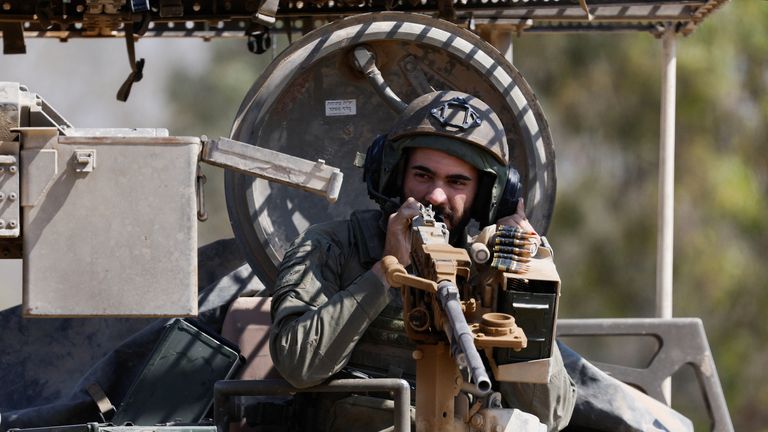An Israeli soldier operates a gun on a military vehicle, near the Israel-Gaza border.
Pic: Reuters