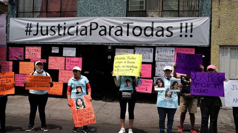 Friends and family holds images of women who have gone missing, during a protest outside an apartment rented by a suspected serial killer in Mexico. Pic: AP