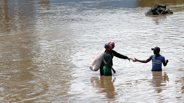 People are forced to wade through deep water following floods. Pic: Reuters