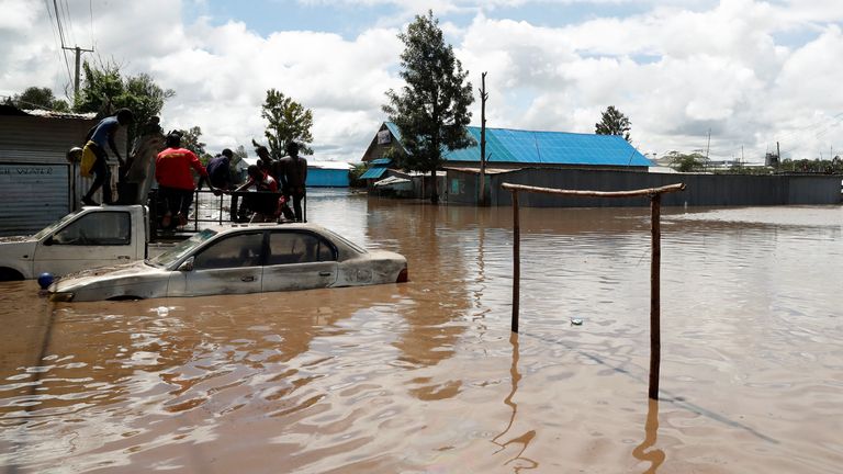 Residents rest atop a pick-up truck partially submerged in Kwa Mang'eli settlement of Machakos county. Pic: Reuters