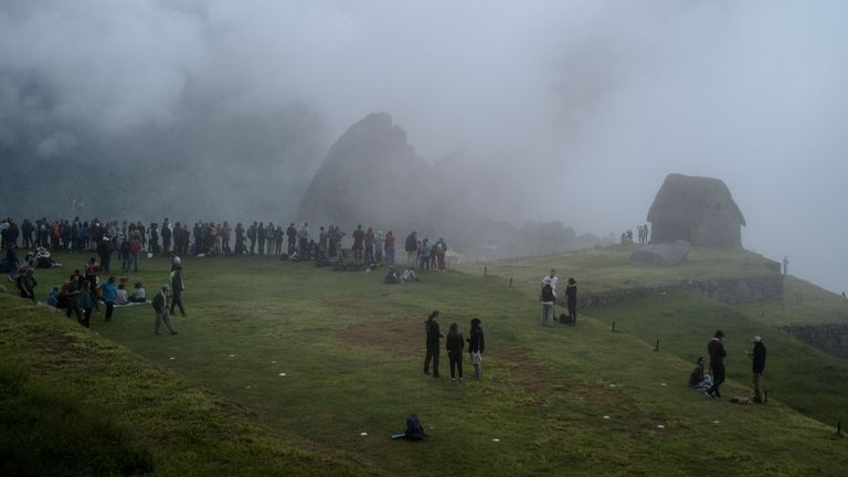Des gens se tiennent devant les ruines incas de Machu Picchu, un pôle d'attraction touristique dont l'accès est limité par les manifestations locales contre la hausse des prix dans le contexte d'une flambée mondiale récemment déclenchée par l'invasion russe de l'Ukraine, à l'extérieur de Cuzco, au Pérou, le 18 avril 2022. Photo prise le 18 avril 2022. REUTERS/Alessandro Cinque