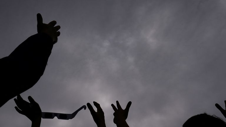 People hold their hands up to the sky, hoping the clouds will part at Dunkirk Lighthouse & Veterans Park Museum in Dunkirk, New York