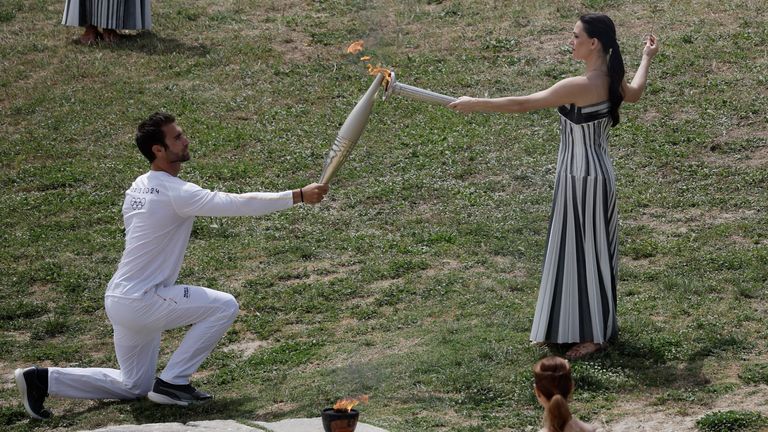 Ms Mina passes the flame to the first torchbearer, Greek rower Stefanos Ntouskos. Pic: Reuters