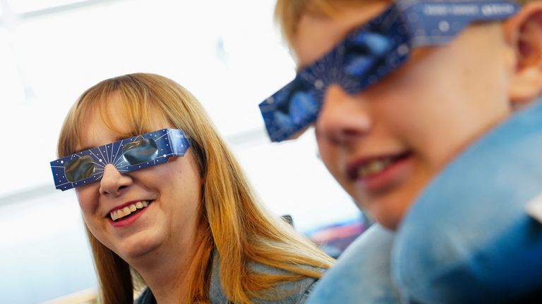 Passengers wear solar eclipse glasses as they get ready to board a plane en route to Detroit, Michigan