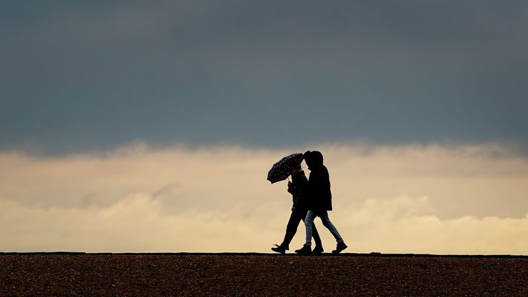 People walk along the beach during rain in Folkestone, Kent, last month. Pic: PA
